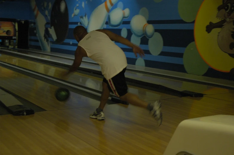 a man in black shorts is bowling a ball