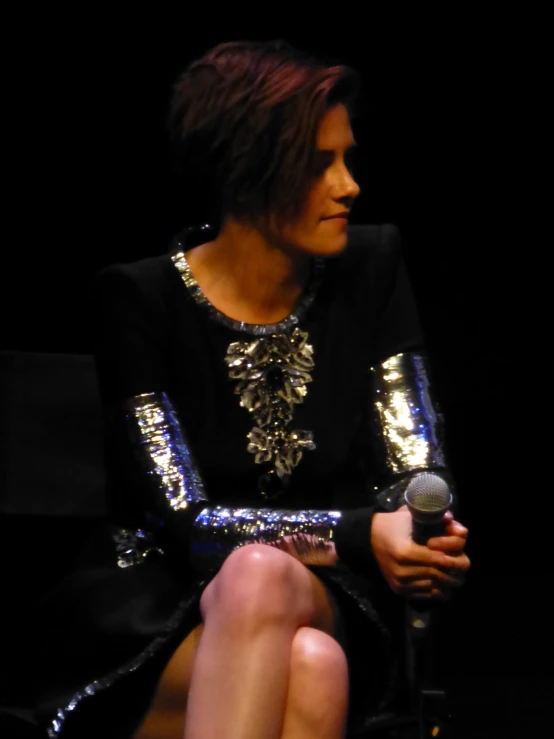 a woman with a microphone sitting on a black surface