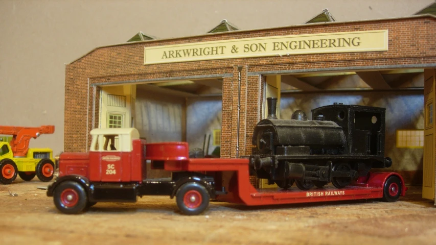 a red and yellow model truck parked in front of a brick building