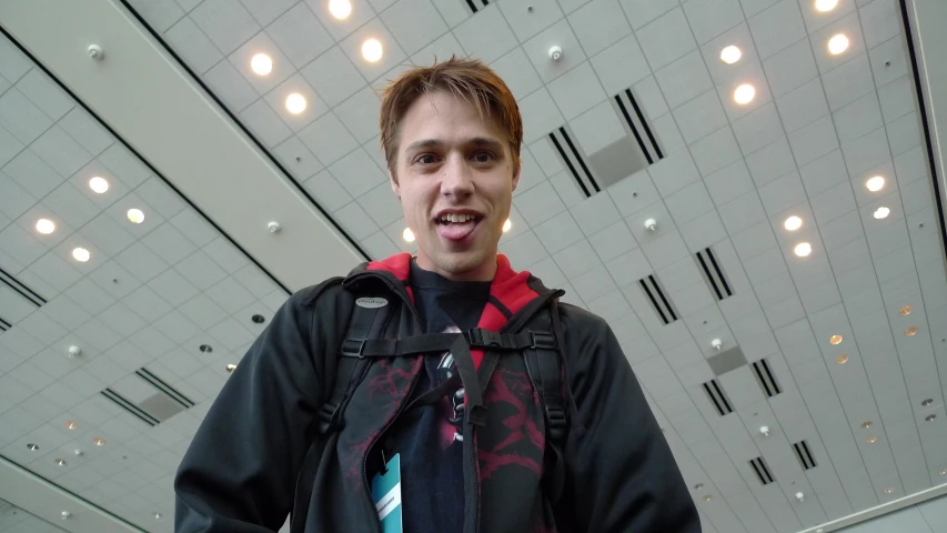 a young man is standing in an empty hall with a hoodie on