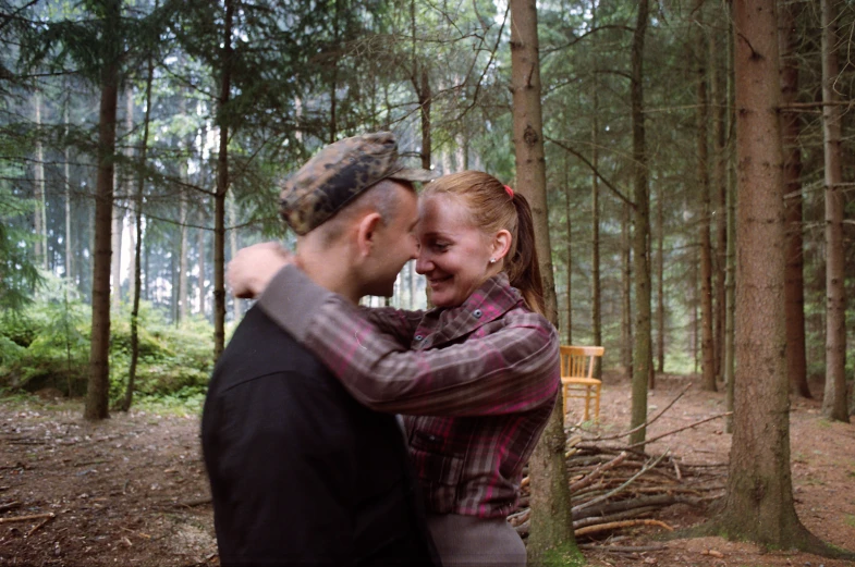 a man and woman are cuddling in the woods