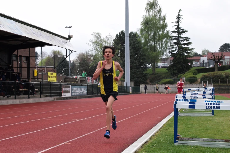 a young man running across a track at a sporting event