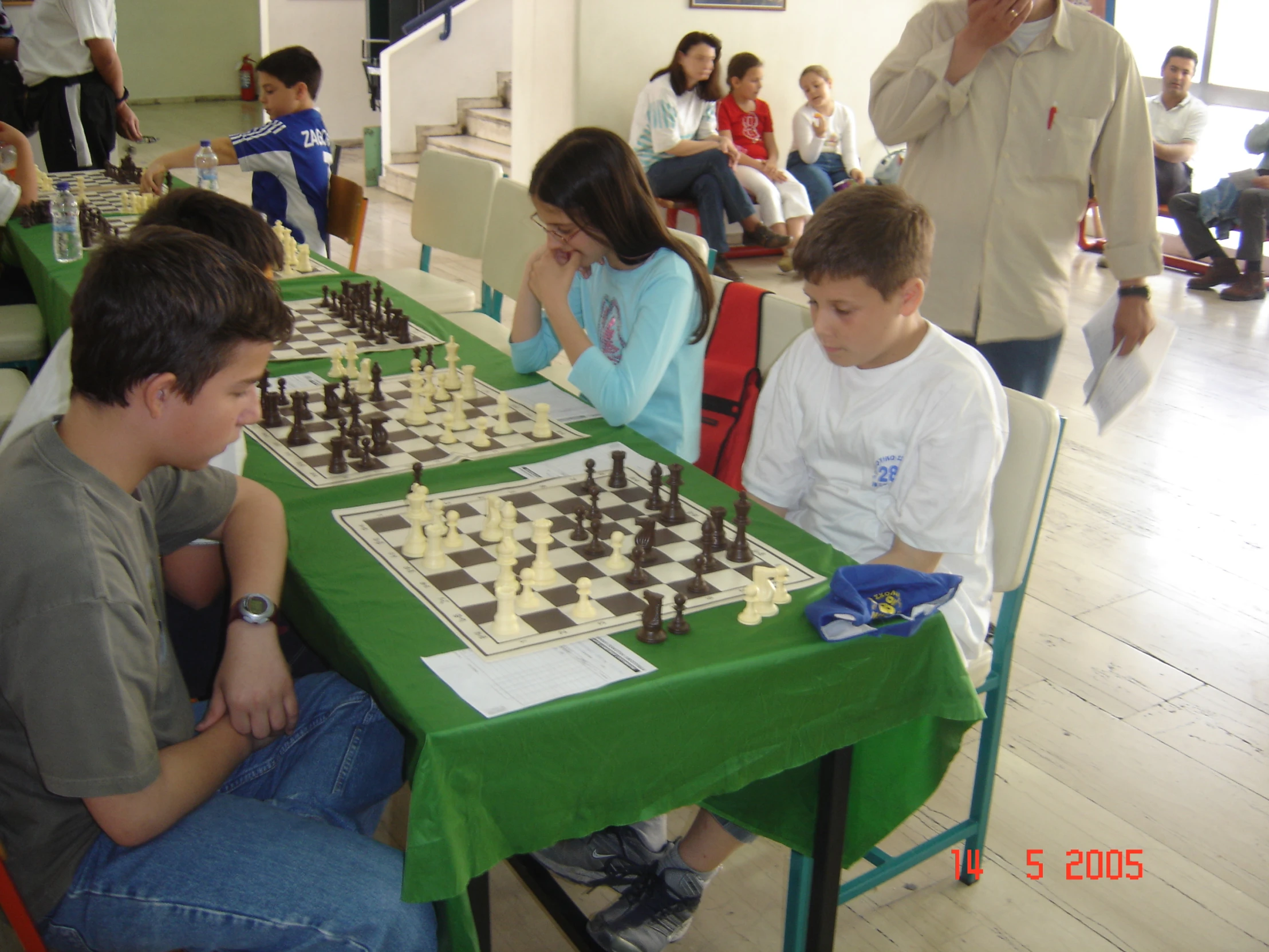 two boys sit at a table with chess pieces on it
