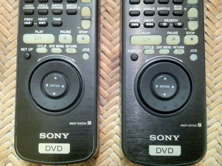 two television remote controls sitting on the ground