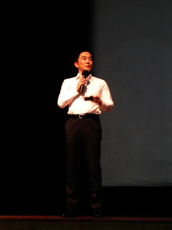 a man in a white shirt and tie holding a microphone