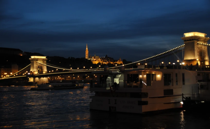 a large boat is in the water under a bridge at night