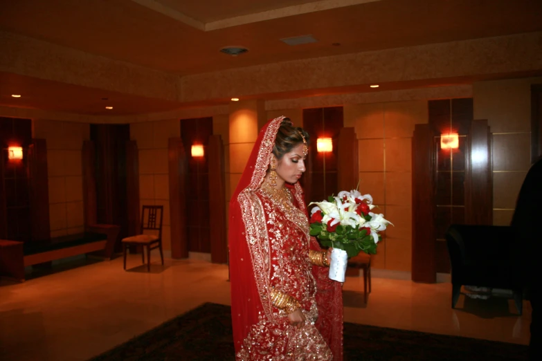 woman in indian red and gold bridal attire with bouquet