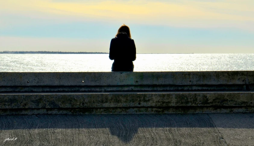 a woman looks out over the ocean from the concrete stairs