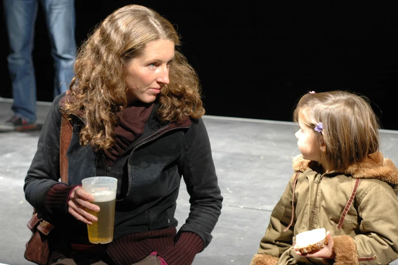 a mother and daughter drinking beverages at a stage