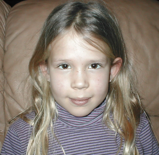 a close up of a child wearing a sweater with long blonde hair