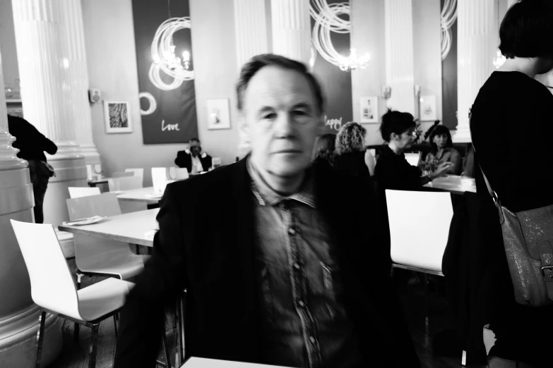 black and white pograph of a man in a restaurant with people eating