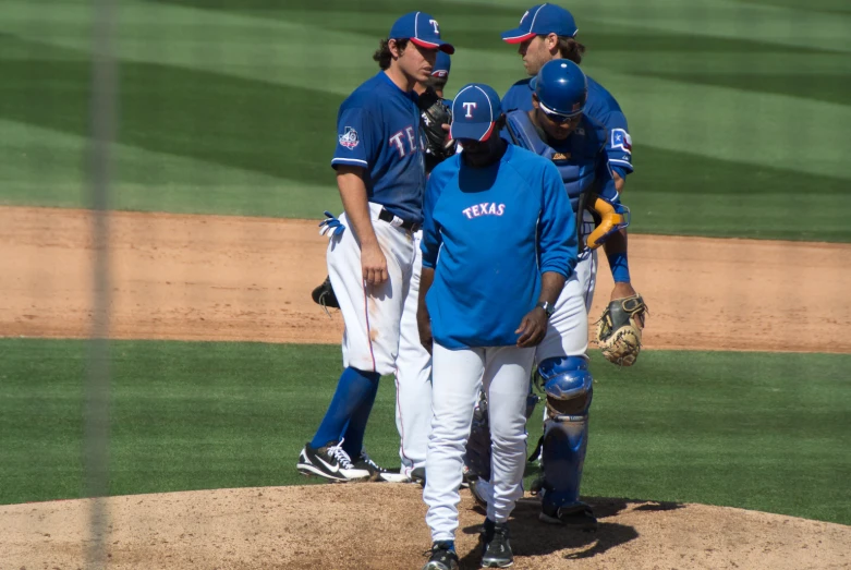 a baseball team huddles around the pitcher's mound