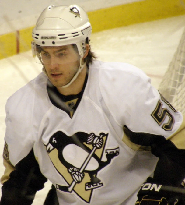 a male hockey player on the ice wearing a penguins uniform