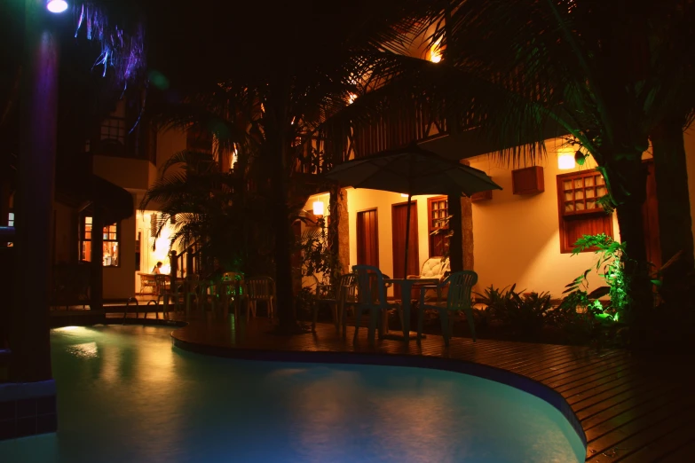 a nighttime s of a swimming pool surrounded by palm trees