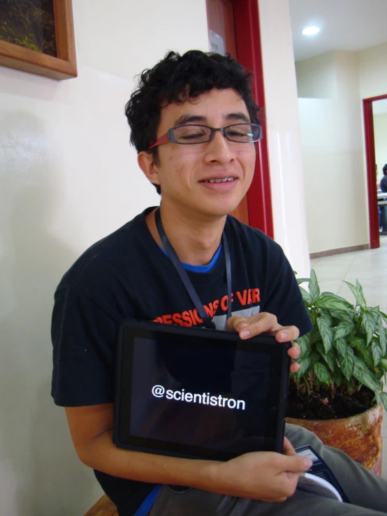 a young man with glasses holding up a tablet