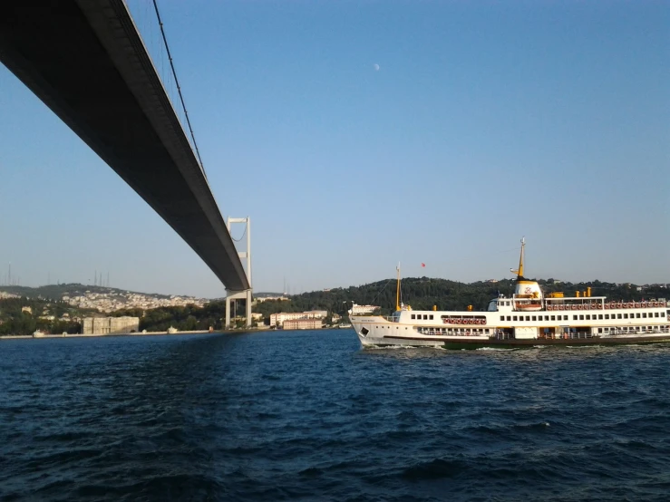 large cruise boat floating below an overpass in a river