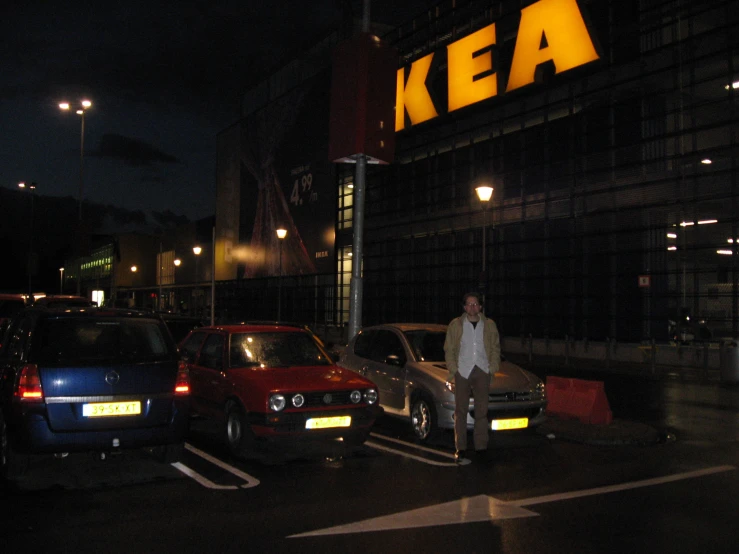 three cars parked in the street at night next to an ikea sign