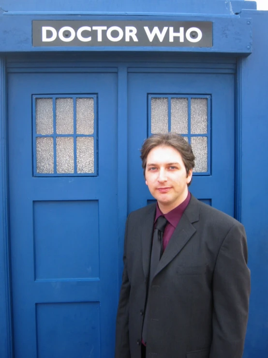 a man in a suit standing in front of a blue door