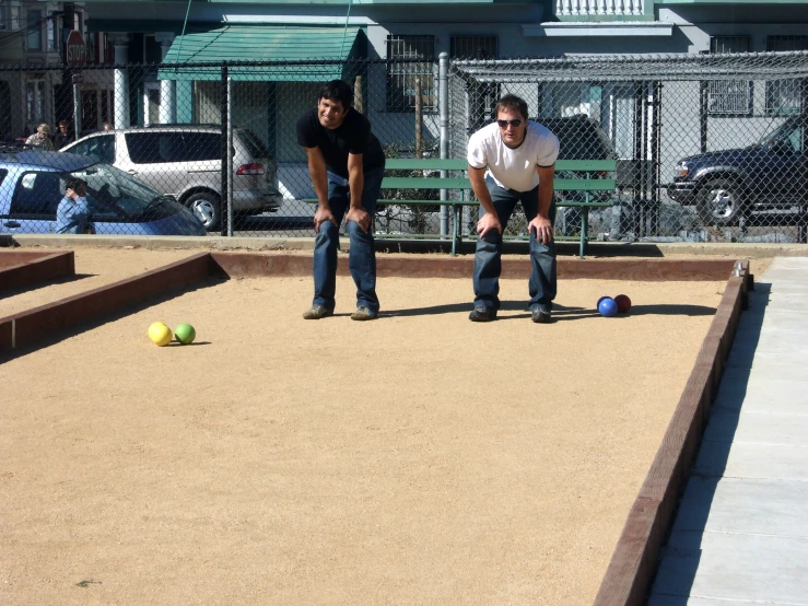 two men playing bowls in a dog park