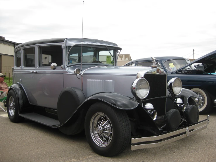 an old grey car sitting in a parking lot