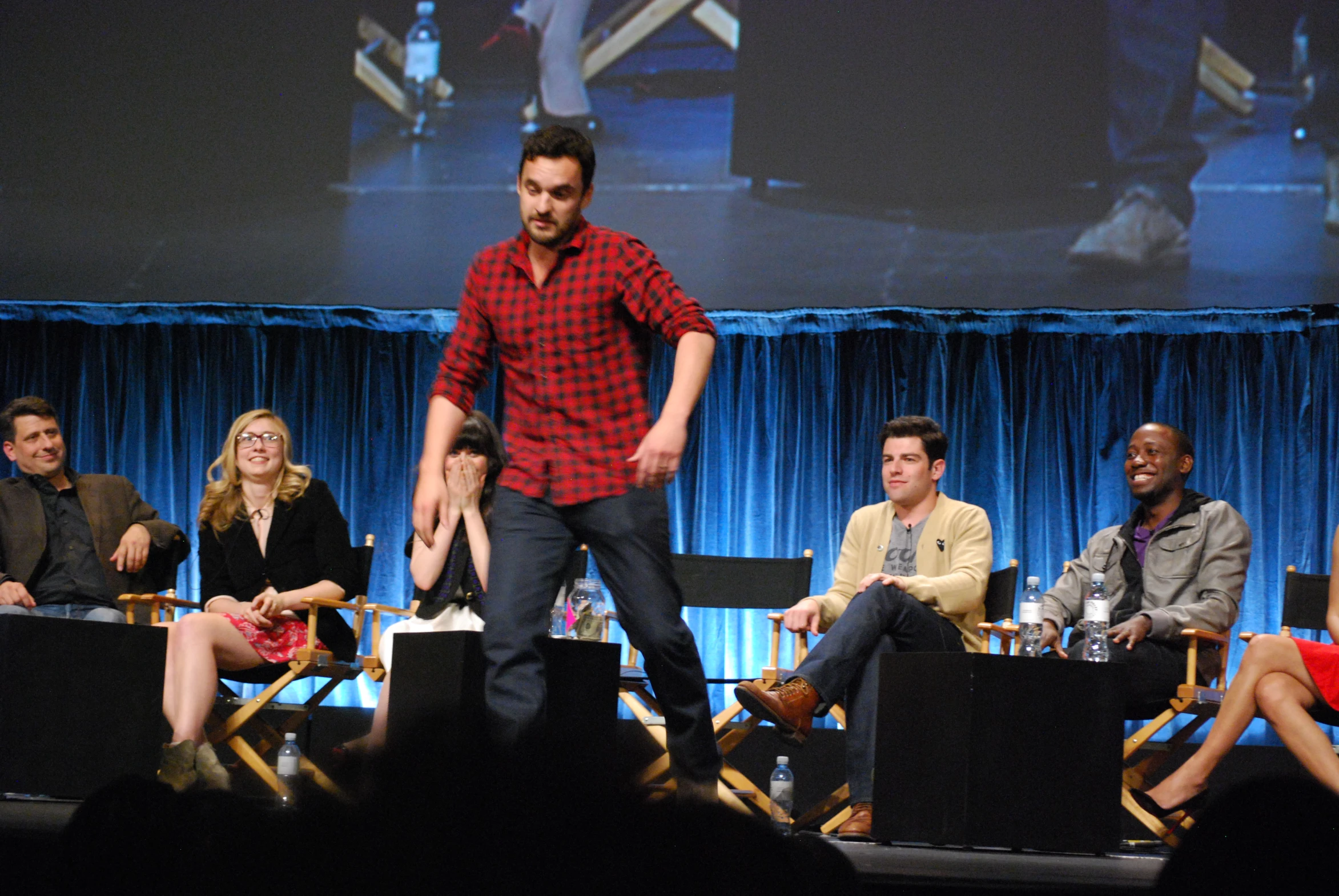 a man walks on stage, surrounded by a group of people