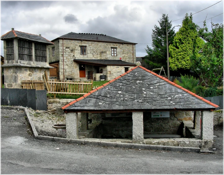 a very small stone building sitting in a rural street