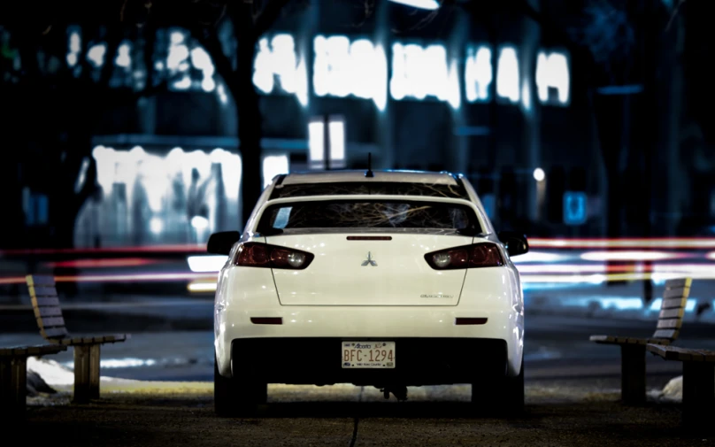 the rear end of a car parked in front of some benches