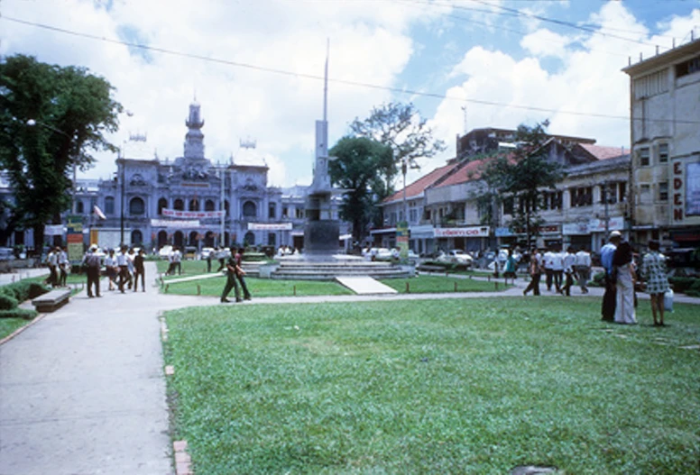 people walk through the green grass of an old, historic town