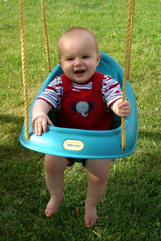 a small boy sitting on a swing with his hands in the air