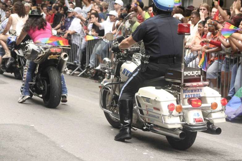 two police men riding on the back of their motorcycle in front of a crowd of people