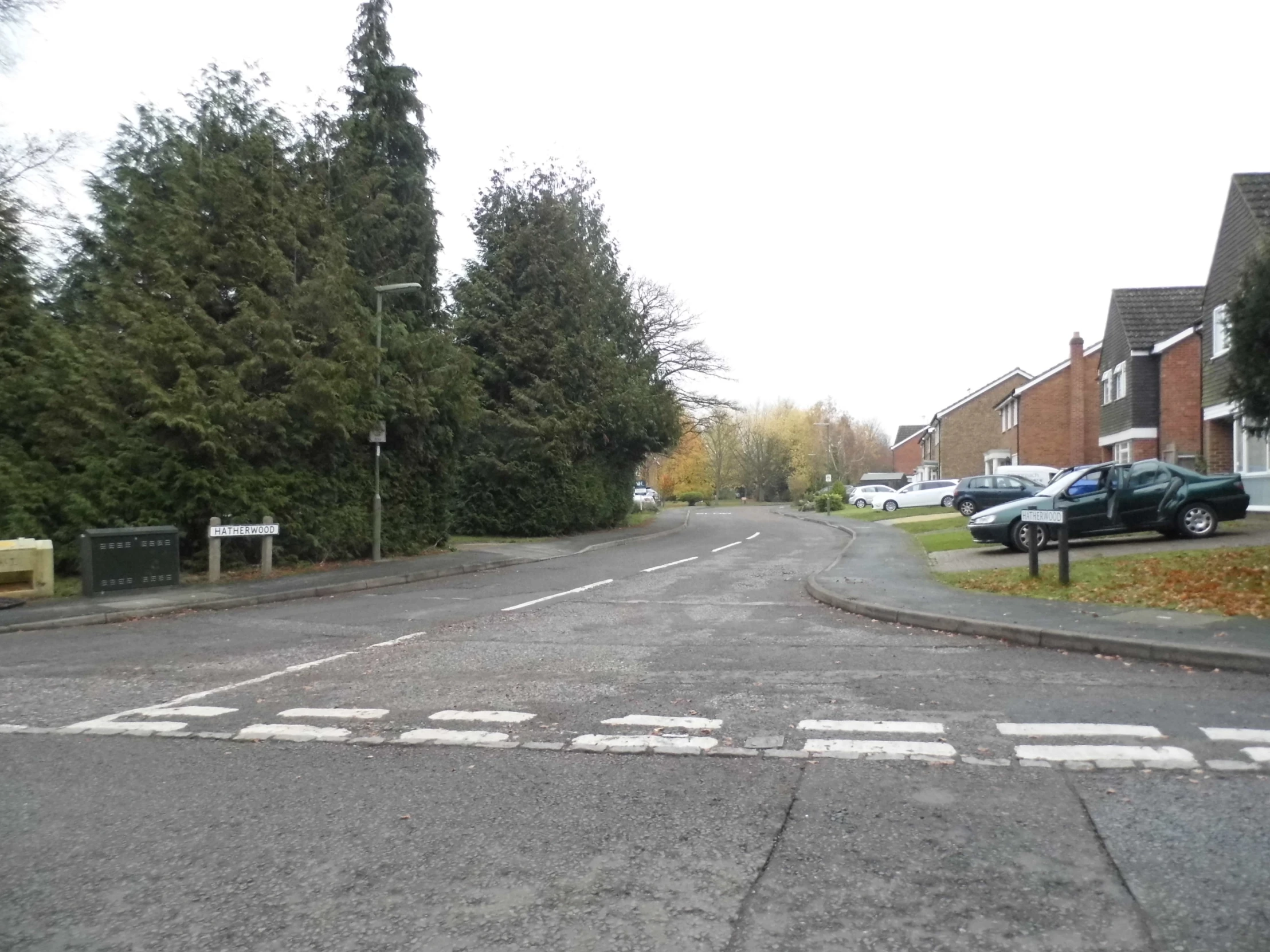 empty roadway with car parks parked next to trees and buildings