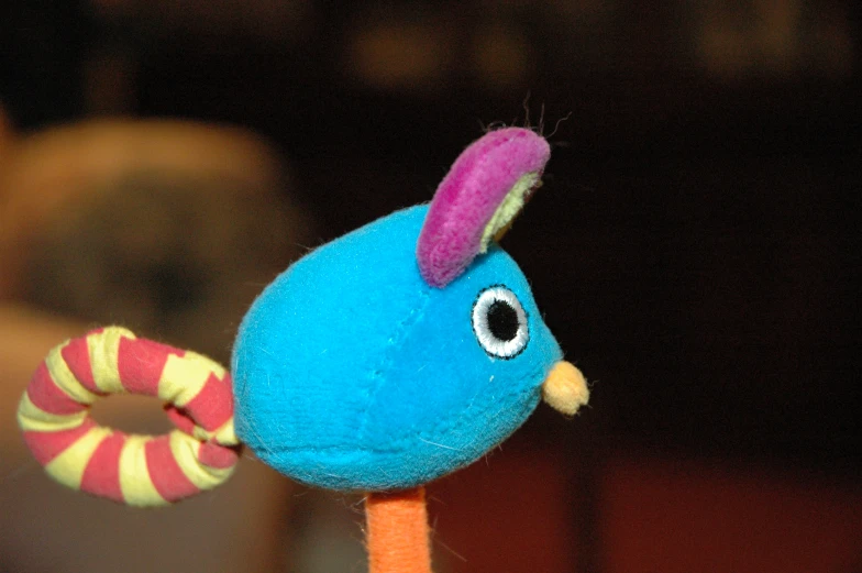 a blue plush bird is perched on a stick