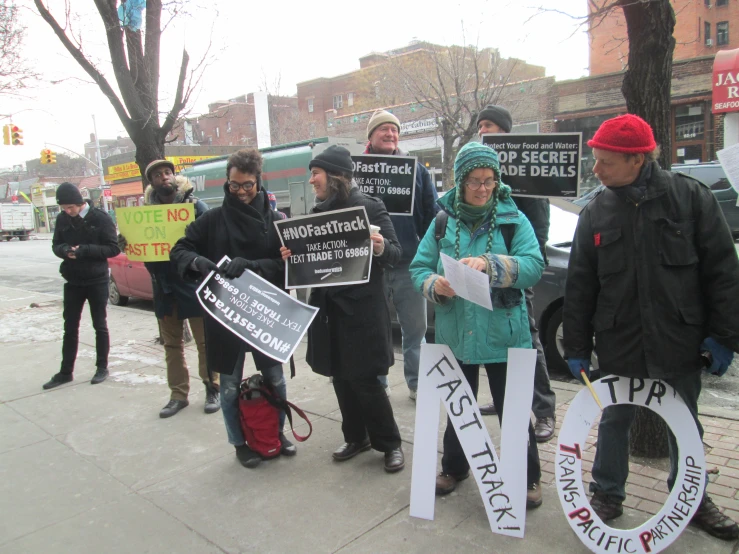 a group of people holding signs while standing on a sidewalk