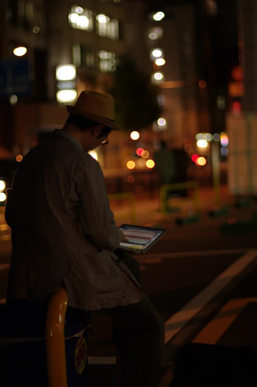 a man sits on a post and holds an electronic device