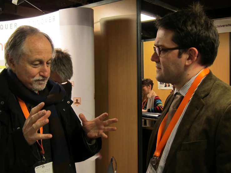 two men speaking in front of a mirror in a room