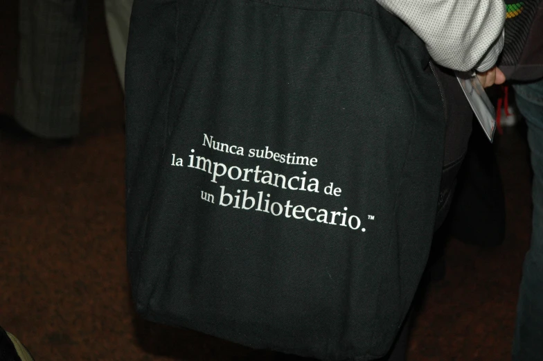 a person holding a black bag with white writing