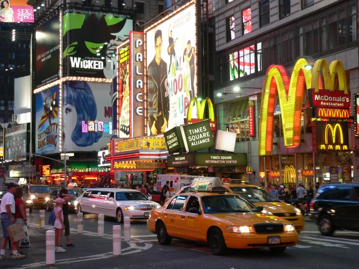 people standing around cars in front of a neon lit restaurant