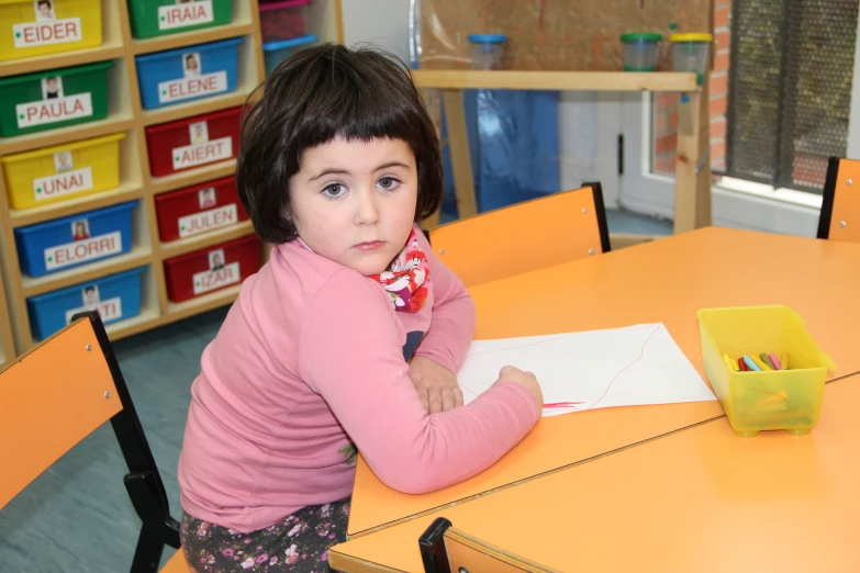 a child in a pink shirt writing with scissors