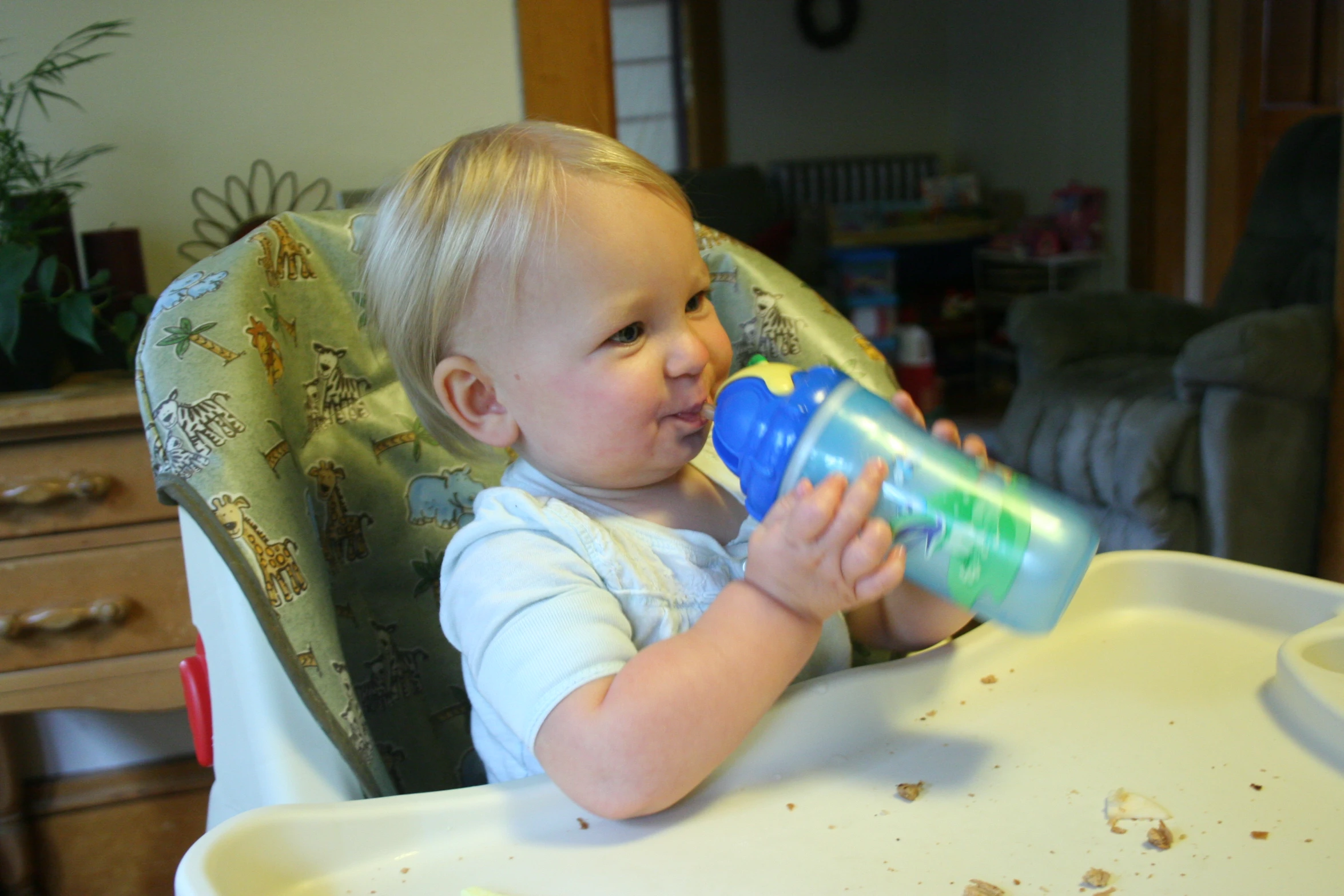 there is a baby holding onto a blue cup