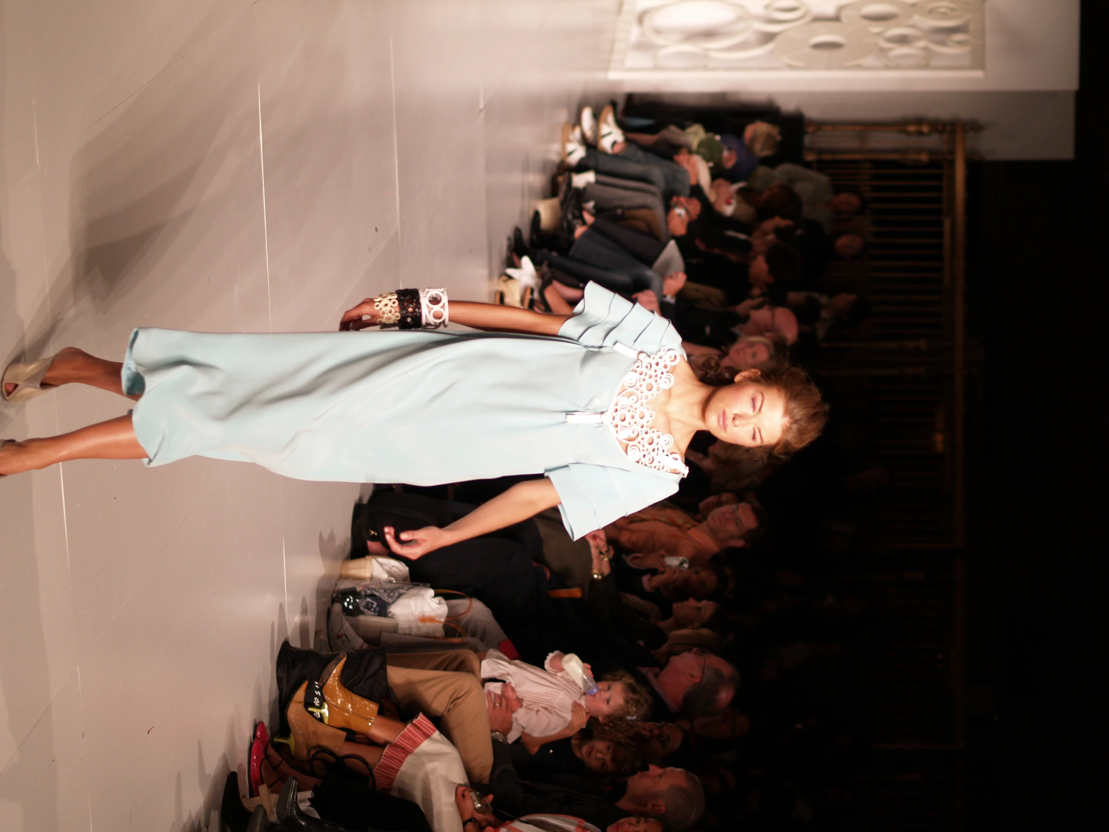 a model wearing a blue dress and shoes in front of a crowd