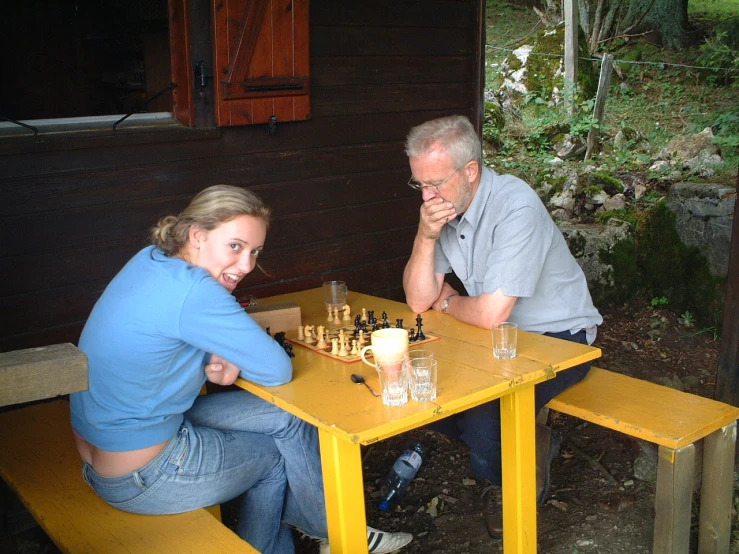 an older man and woman sit at a table playing chess