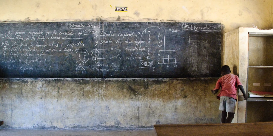 two people writing on a blackboard in a room