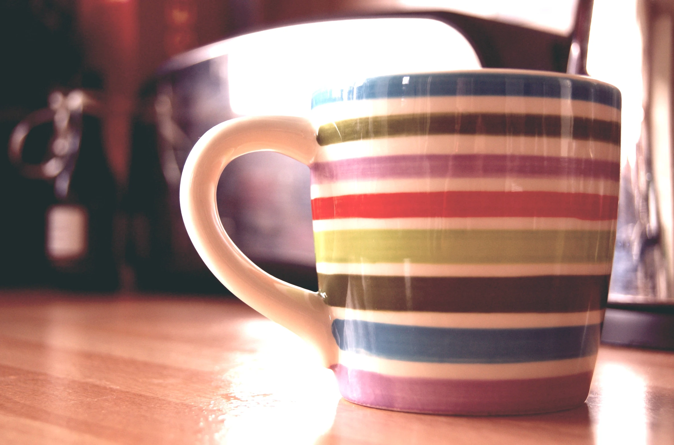 an empty striped coffee cup sits on the table next to another container