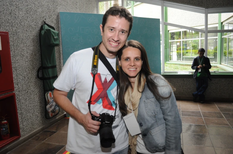 two people standing together in a room with a camera and other equipment