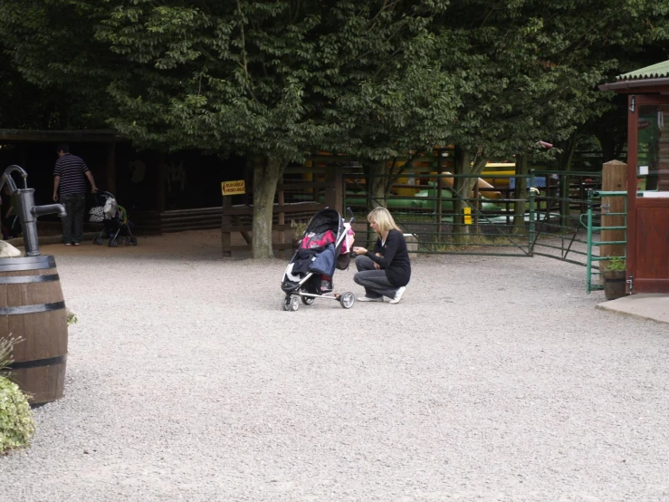 a child sitting on a stroller and a lady sitting by the park