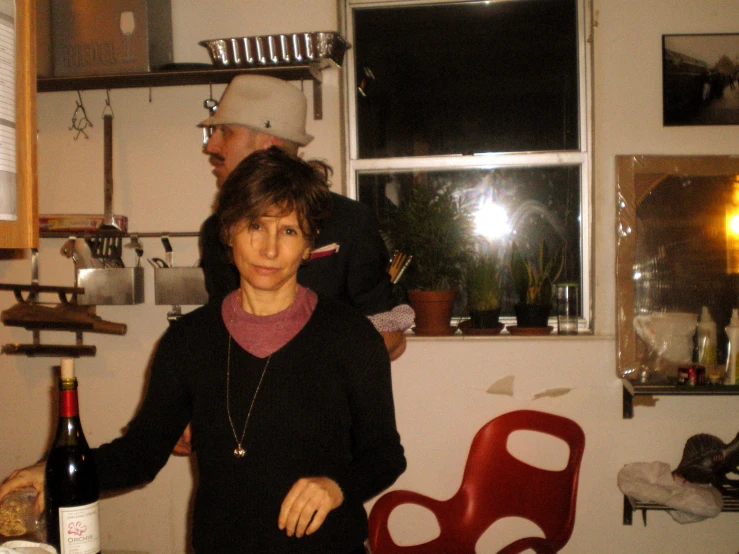 two people in a kitchen with bottles of wine