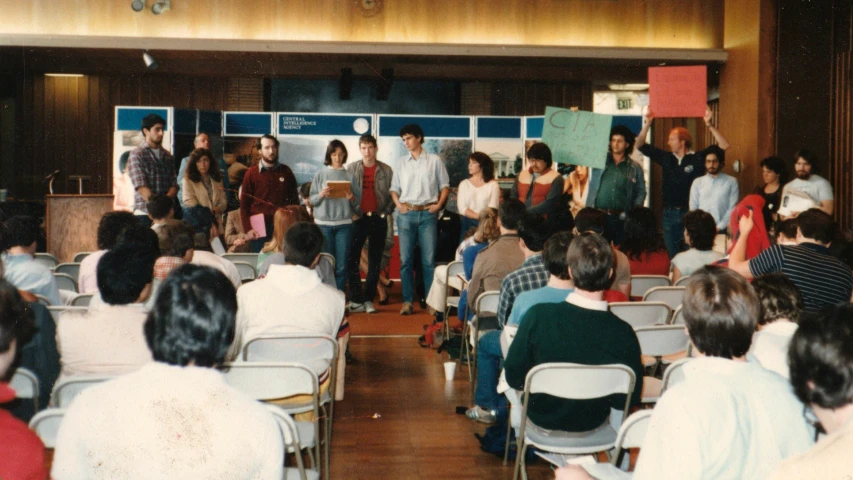 several people standing on a stage and listening to each other