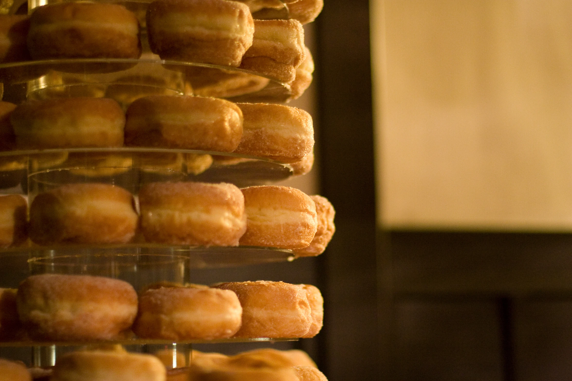 a display case holding lots of doughnuts in the kitchen