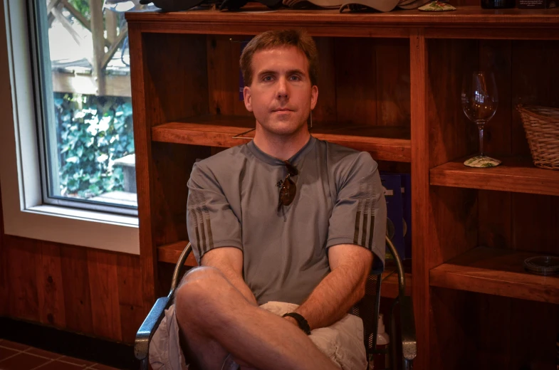 a man sitting in front of a bookshelf filled with lots of shelves