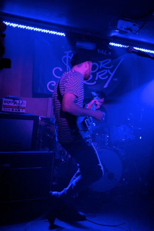 a man on stage with purple lighting and blue colors